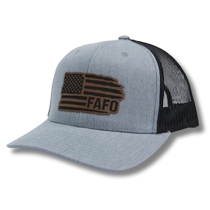 May include: A gray and black trucker hat with a brown leather patch featuring an American flag and the text "FAFO".