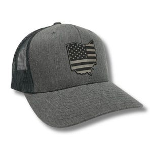May include: A gray and black trucker hat with a black and white American flag design in the shape of the state of Ohio.