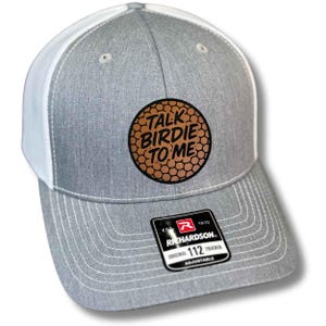May include: Gray and white trucker hat with the text "TALK BIRDIE TO ME" on a brown patch. The hat has a curved brim and a mesh back. The Richardson brand label is visible.