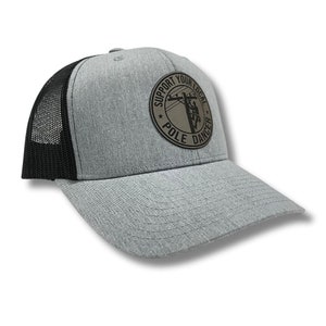 May include: A gray and black trucker hat with a brown leather patch that says "Support Your Local Pole Dancer".