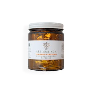 May include: A glass jar with a white lid containing turmeric curcumin and moringa oleifera capsules. The label reads "All Moringa Turmeric Curcumin & Moringa Oleifera Capsules".