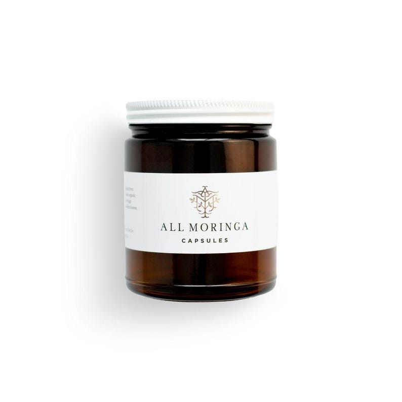 May include: A brown glass bottle with a white lid and a white label that says "ALL MORINGA CAPSULES".
