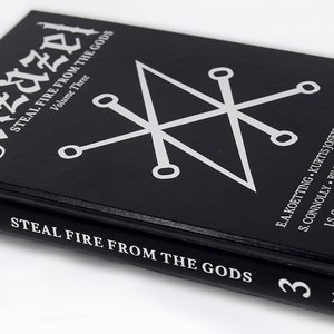 Puede incluir: Un libro negro de tapa dura titulado "Azazel: Steal Fire From The Gods, Volume Three" con un s&iacute;mbolo de pentagrama plateado en la portada. El lomo del libro tiene el t&iacute;tulo y el n&uacute;mero de volumen en letras plateadas. La contraportada enumera a los autores y la frase "Become a Living God" en letras plateadas.