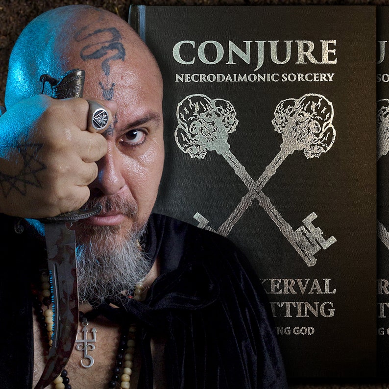 Puede incluir: Un hombre con barba y tatuajes en la cara y los brazos sostiene un cuchillo frente a su cara. Lleva una t&uacute;nica negra y un collar con un colgante de tridente. El fondo es un libro verde oscuro con letras plateadas que dicen "CONJURE NECRODAIMONIC SORCERY" y una imagen plateada de dos llaves cruzadas con calaveras en los extremos.