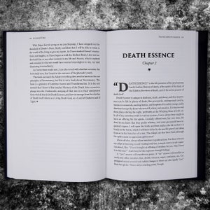 May include: Open book with a white background and black text. The title of the book is "Death Essence" and the chapter is "Chapter 2". The text on the page discusses the concept of "Death Essence" and how it is felt in places of darkness, death, and decay. The text also mentions the importance of offering spirits whiskey or cognac as an offering.