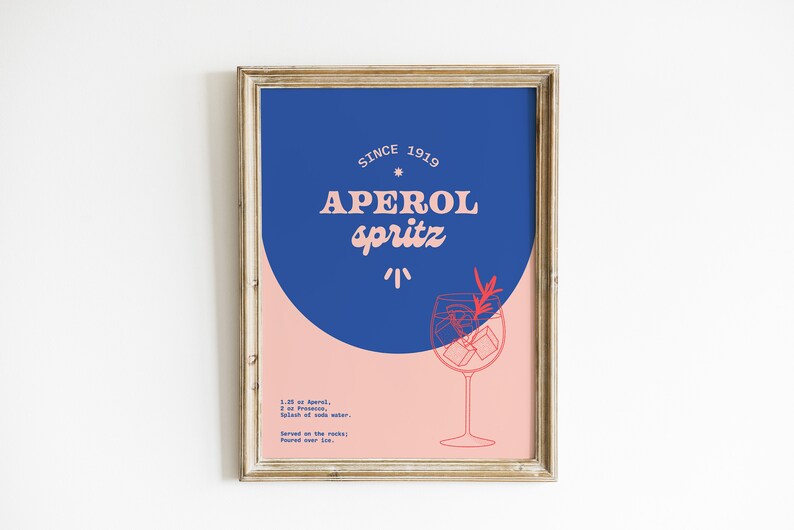 May include: A framed poster with a blue and pink background. The poster features a stylized illustration of a glass of Aperol Spritz with the text "SINCE 1919 APEROL SPRITZ" and the ingredients for the cocktail.