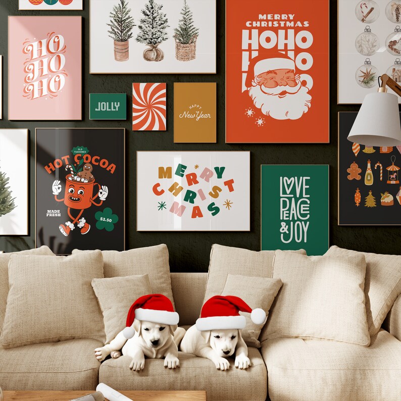Op de afbeelding: Een woonkamer die is versierd voor kerstmis met een bank, twee witte puppy's met kerstmanmutsen en verschillende kerstthemaposters aan de muur. De posters bevatten zinnen als "Merry Christmas", "Ho Ho Ho", "Love Peace & Joy" en "Hot Cocoa".