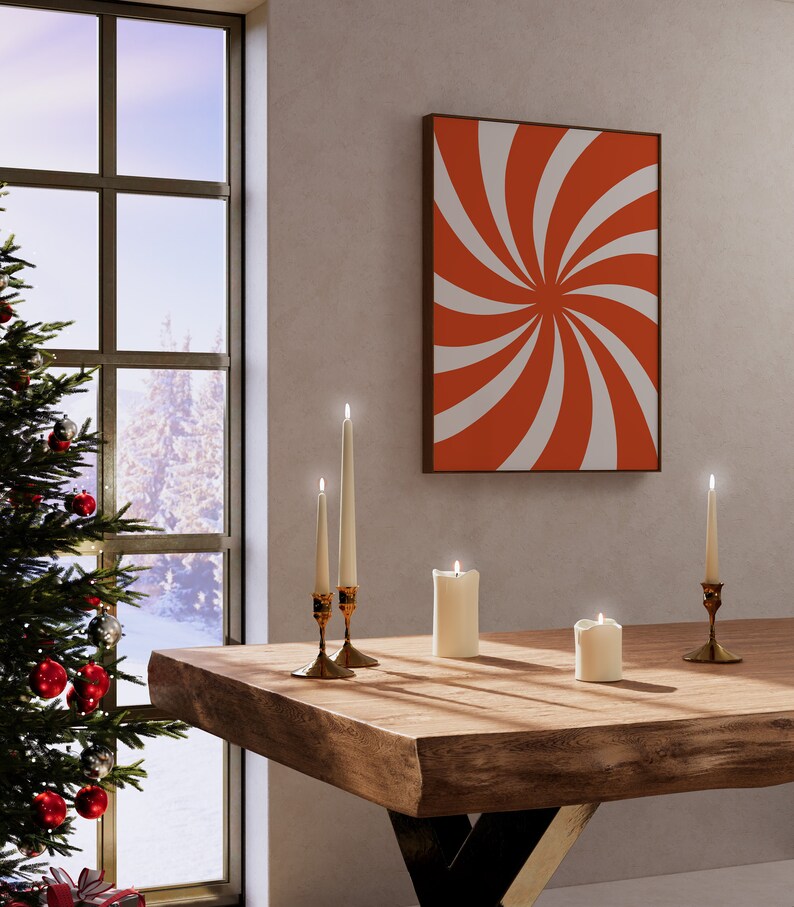 Op de afbeelding: Een houten tafel met vier witte kaarsen en twee gouden kandelaars. De kaarsen zijn aangestoken en de tafel staat voor een raam met een kerstboom en een rood-wit abstract schilderij aan de muur.
