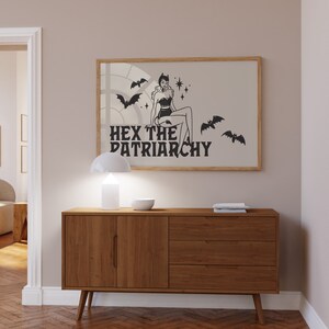 May include: A black and white illustration of a woman in a witch costume with bats and stars. The text "HEX THE PATRIARCHY" is below the image.