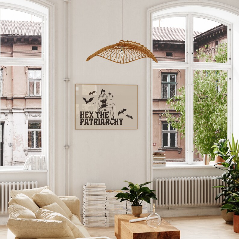 May include: A beige room with a large window, a wicker pendant light, and a framed print with the text "Hex the Patriarchy" and a black and white illustration of a woman with bats.