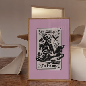 The reader tarot card print. A skeleton reading a book. Pink background, beige and black foreground. Occult witchy reading print. Perfect gift for book lovers.