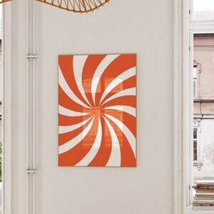 Op de afbeelding: Een ingelijste print van een rood en wit spiraalontwerp. De spiraal is gecentreerd in de lijst en heeft een witte achtergrond.