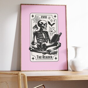 The reader tarot card print. A skeleton reading a book. Pink background, beige and black foreground. Occult witchy reading print. Perfect gift for book lovers.