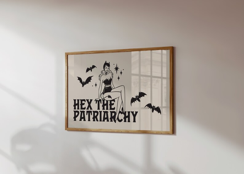 May include: A framed print featuring a black and white illustration of a woman in a witch costume with bats and stars. The text "HEX THE PATRIARCHY" is below the illustration.