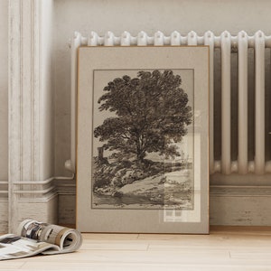 May include: A framed black and white print of a tree with a tower in the background. The print is in a light brown frame with a white mat.