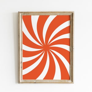 Op de afbeelding: Een ingelijst afdruk met een draaiend oranje en wit patroon. Het patroon lijkt op een zonnestralen of een spiraal.