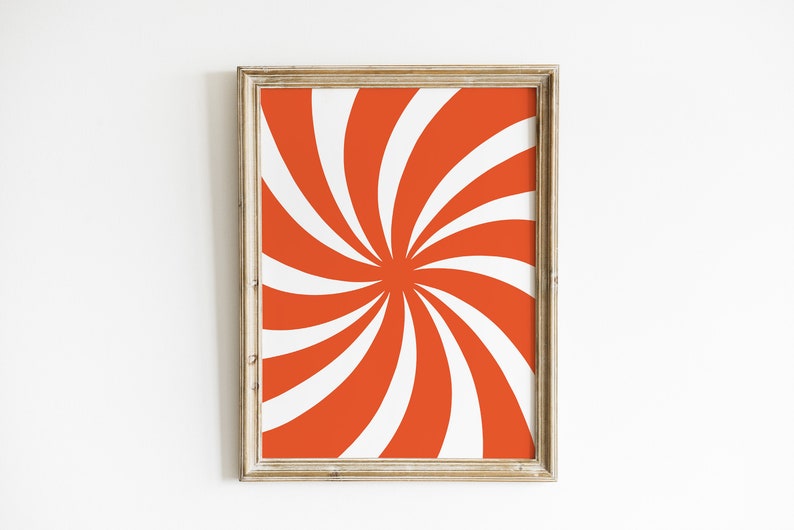 Op de afbeelding: Een ingelijst afdruk met een draaiend oranje en wit patroon. Het patroon lijkt op een zonnestralen of een spiraal.
