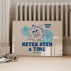 May include: A beige poster with a blue clock face with eyes and a key. The clock is surrounded by a blue star and a blue circle. The text on the poster reads "There has never been a time I wasn't loved."