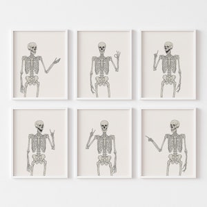 May include: Set of six printable art prints featuring a skeleton in different poses. Each print shows a skeleton with a different hand gesture, including a peace sign, a thumbs up, and a pointing finger. The prints are all in black and white and have a minimalist aesthetic.
