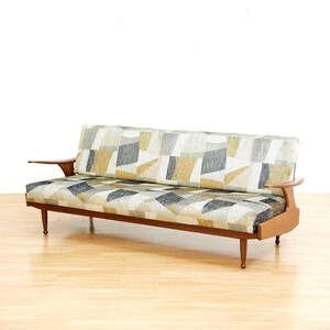 May include: Mid-century modern sofa with a geometric patterned fabric in shades of gray, yellow, and beige. The sofa has a wooden frame, armrests, and tapered legs. The sofa is approximately 78 inches long.
