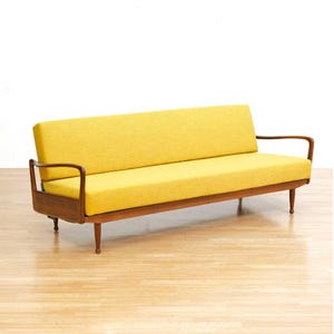 May include: A mid-century modern sofa with a bright yellow cushion and wooden frame. The sofa has a low profile with curved armrests and tapered legs. The overall design is minimalist and stylish, perfect for a living room or lounge area.