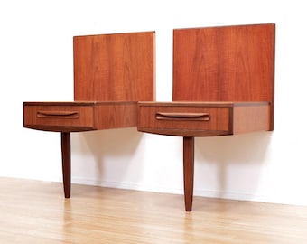 May include: A pair of mid-century modern teak wall-mounted nightstands with single drawers and a single leg.