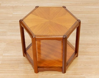 May include: A mid-century modern hexagonal side table. The table is made of wood with a light brown finish. The top has a geometric pattern, and there is a lower shelf. The table is approximately 24 inches wide and 20 inches tall.