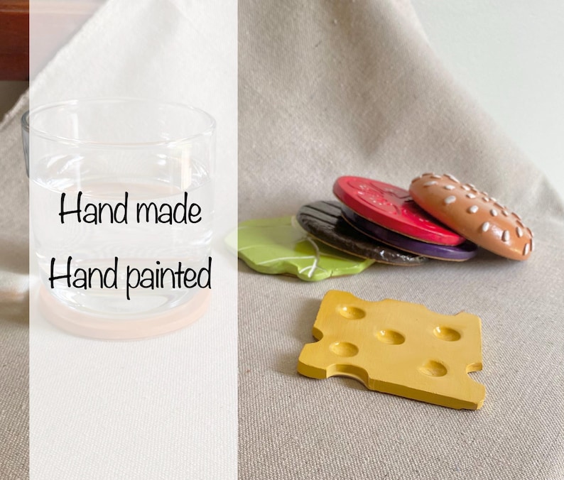 May include: Hand painted wooden food play set featuring a glass jar, a cheese slice, a hamburger bun, a lettuce leaf, and a tomato slice. The set is hand made and features realistic details.