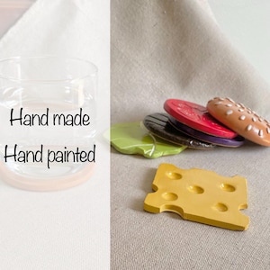 May include: Hand painted wooden food play set with a glass jar, a cheese slice, a hamburger bun, a lettuce leaf, and a tomato slice. The set is hand made and features realistic details.