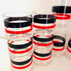 May include: Set of six clear glass tumblers with black and red stripes. The tumblers are stacked on top of each other.