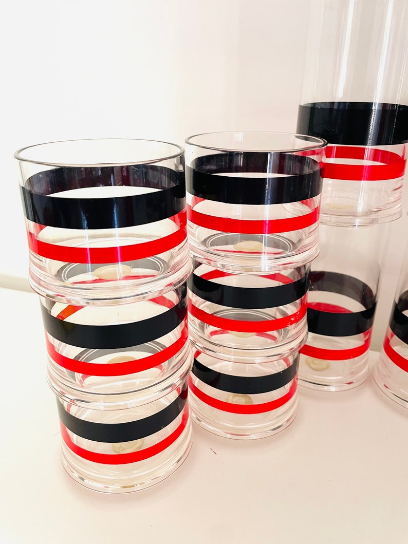 May include: Set of six clear glass tumblers with black and red stripes. The tumblers are stacked on top of each other.