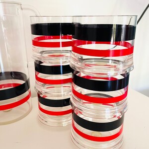May include: Set of six clear glass tumblers with red and black striped designs. The tumblers are stacked on top of each other.