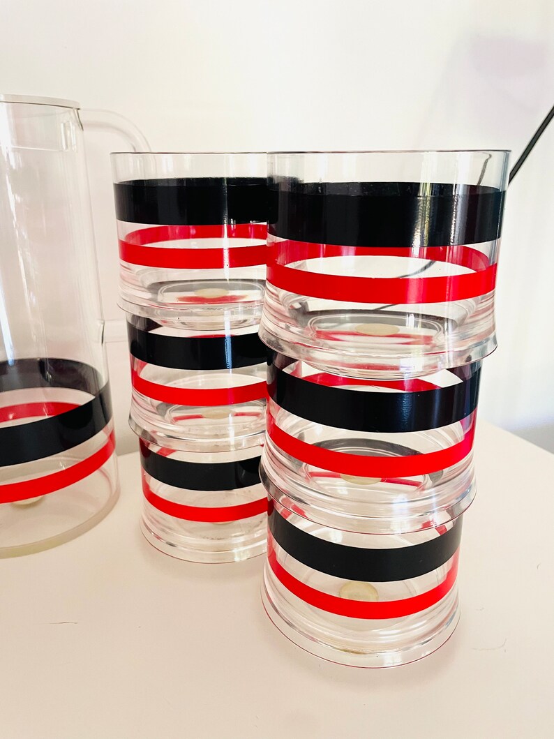 May include: Set of six clear glass tumblers with red and black striped designs. The tumblers are stacked on top of each other.