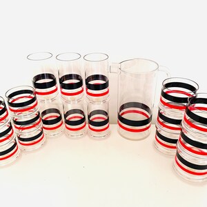May include: Set of clear glass tumblers and a pitcher with black and red striped designs.