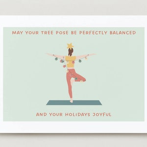 May include: A Christmas card with a woman in a tree pose, wearing a yellow shirt and red pants, with a string of lights around her. The text on the card reads "May your tree pose be perfectly balanced and your holidays joyful."