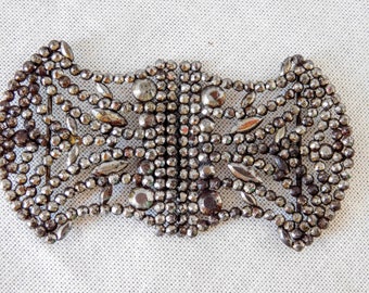 May include: A silver-toned metal buckle with a decorative design made of small beads and teardrop-shaped pieces.