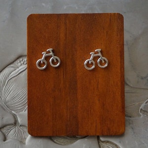 Può includere: Un paio di orecchini a forma di bicicletta in argento. Gli orecchini sono piccoli e delicati, e presentano un design semplice di una bicicletta.