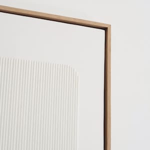 May include: A modern, minimalist artwork featuring a white, textured panel with vertical lines and a rectangular shape. The artwork is framed in natural wood, creating a clean and contemporary aesthetic.