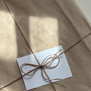 May include: A wrapped package in brown paper, tied with twine and a small white card. The card has the text "STILL LINES STUDIO" and handwritten script. The twine is tied in a bow.