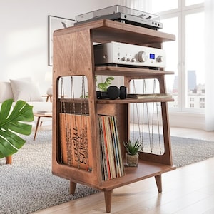 May include: A brown wooden media console with four tiers, featuring a top surface for a turntable, a middle shelf for an amplifier, and lower sections with vertical cord dividers for vinyl record storage, supported by four tapered wooden legs.