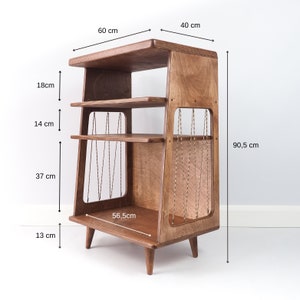 May include: A brown wooden shelving unit with four tiers, supported by four tapered legs. The sides feature a cutout design with thin, braided cord accents. Dimensions are 60 cm wide, 40 cm deep, and 90.5 cm high, with specific shelf spacing.