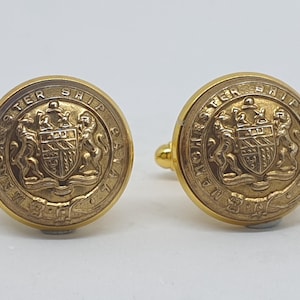 Puede incluir: Un par de gemelos de oro con un escudo de armas detallado y el texto "Dominion Ship Canada" alrededor del borde.