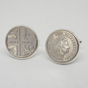 Puede incluir: Gemelos plateados con monedas británicas de cinco peniques. Un gemelo muestra el diseño de la moneda con las palabras "FIVE PENCE". El otro muestra el perfil de la reina Isabel II y el año 2022.