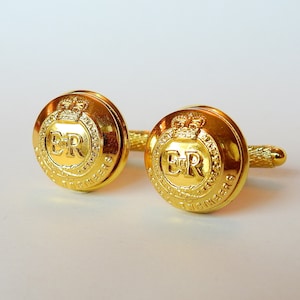 May include: A pair of gold cufflinks featuring the Royal Engineers crest with the inscription "Royal Engineers" and the royal cypher "ER".