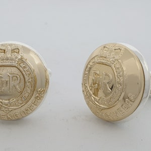 Puede incluir: Un par de gemelos de oro y plata con el escudo de los Royal Engineers con la inscripción "Royal Engineers" y el monograma real "ER".
