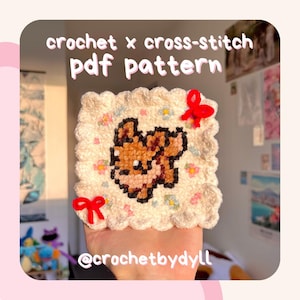 May include: A square, off-white crochet piece with a pixelated brown bear design, surrounded by small flowers and two red bows. The text "crochet x cross-stitch pdf pattern" is at the top, with the Instagram handle "@crochetbydyll" at the bottom.