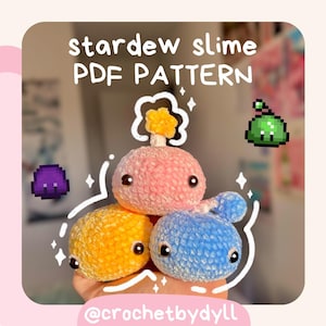 May include: Crochet pattern for Stardew Valley slime plushies. The pattern includes three slimes: a pink slime with a yellow flower on top, a yellow slime, and a blue slime. The pattern is available as a PDF download.