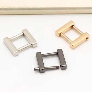 Puede incluir: Tres hebillas de metal en forma de D en plata, oro y negro.