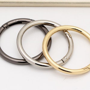 May include: Three metal rings in different finishes: silver, gold, and black. The rings are all the same size and have a swivel clasp.