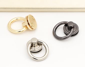 Könnte beinhalten: Drei Metall-Ringverschlüsse in Gold-, Silber- und Schwarz-Finish. Jeder Verschluss hat einen runden Ring und eine dekorative, strukturierte Basis.